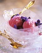 Strawberry ice cream with candied violets and gold spoon