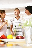 Three young people drinking white wine in kitchen