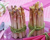 Bundles of white asparagus on purple plate