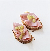 Two open ham sandwiches with soft cheese and chutney