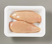 Two chicken breast fillets on plastic tray