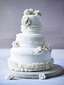 Three-tiered white wedding cake decorated with fondant flowers