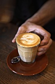 Barista holding a glass of caffè latte