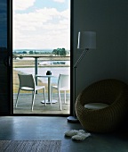 Round wicker chair in hotel room with purist wooden terrace and broad view of landscape