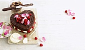 Heart-shaped cake with raspberries, cream and rose petals