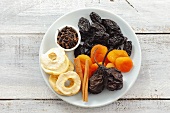 Assorted dried fruit, cinnamon sticks and cloves on plate