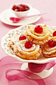 Fried pastries with glacé cherries and icing sugar