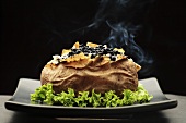 Steaming baked potato with black caviar