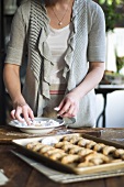 Woman rolling crescent biscuits in icing sugar