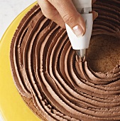 Piping chocolate cream onto cake 