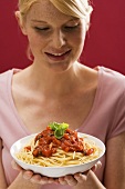 Woman holding spaghetti with tomato sauce