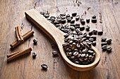 Coffee beans, wooden spoon and cinnamon sticks on wooden background
