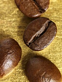 Four coffee beans on gold background (close-up)