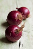 Three red onions on wooden background