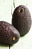 Two avocados on wooden background