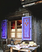 Various French Alpine cheeses outside a wooden chalet