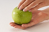 A pair of hands holding a green apple