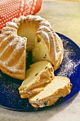 Gugelhupf with raisins and icing sugar, partly sliced