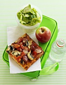 Pizza, apple and salad on lunch box