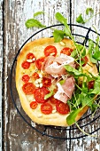 Pizza topped with tomatoes and Parma ham