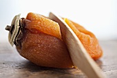 A dried Japanese persimmon being sliced