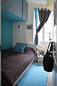 Blick in farblich abgestimmtes Schlafzimmer mit Einzelbett unter Hängeschränken