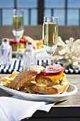 A fish burger and a glass of champagne on a table overlooking the sea