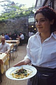 Waitress serving pasta dish, Tuscany, Italy
