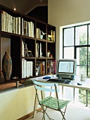 Simple workstation in front of loft window and partition shelving on low wall