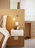 Kopfteil eines Bettes als halbhoher Raumteiler mit integriertem Wandlicht und Nachttisch