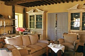 Living room with double doors, two display cabinets, sofa and armchairs with deep upholstery and a round coffee table set with a white cloth