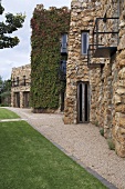 Bewachsenes Landhaus mit Natursteinmauern einer Festung ähnelnd, mit Parkanlage