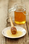 Honey on a plate with a honey spoon with a jar of honey in the background