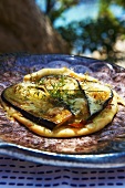 A pizza with aubergines, cheese and herbs