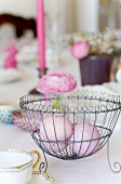 Pink Easter eggs in a wire basket on a table decorated for Easter