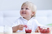 A small child eating squashed strawberries