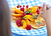 A child eating pancakes with fresh fruit