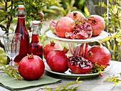 Pomegranates on tiered stand and bottles of pomegranate juice