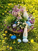 Flowers and Easter Bunny in Easter basket in field of dandelions