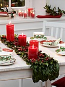Table runner of holly leaves with four red candles
