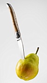 Knife sticking into pear