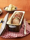 Oven-baked meatloaf wrapped in savoy cabbage and bacon