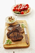 Grilled beefsteaks, garlic butter and tomato salad