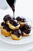 Pouring chocolate sauce over profiteroles