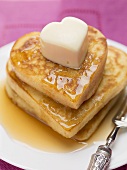 Heart-shaped pancakes with maple syrup and butter