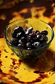 Pickled black olives in a small glass bowl