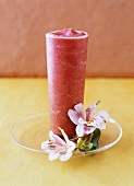 Strawberry-vanilla drink beside flowers on a glass plate