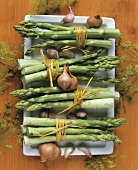 Bundles of green asparagus spears, onions and garlic