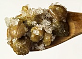 Salted capers on a wooden spoon