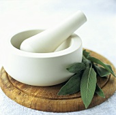 Stone mortar and pestle on a kitchen board with sage